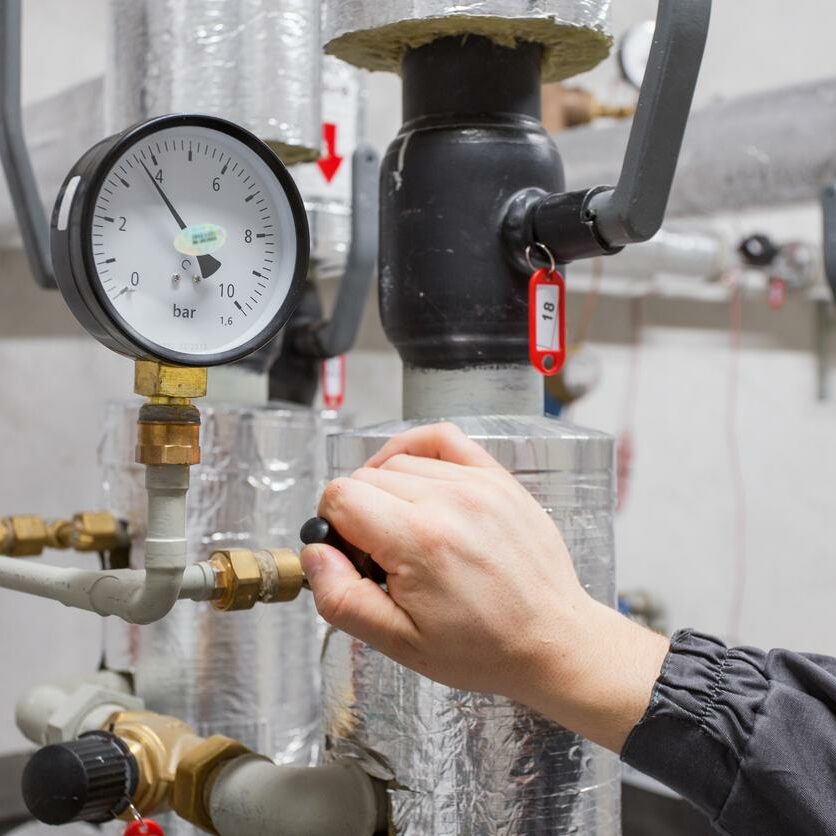 Technician checking water pressure in boiler room.